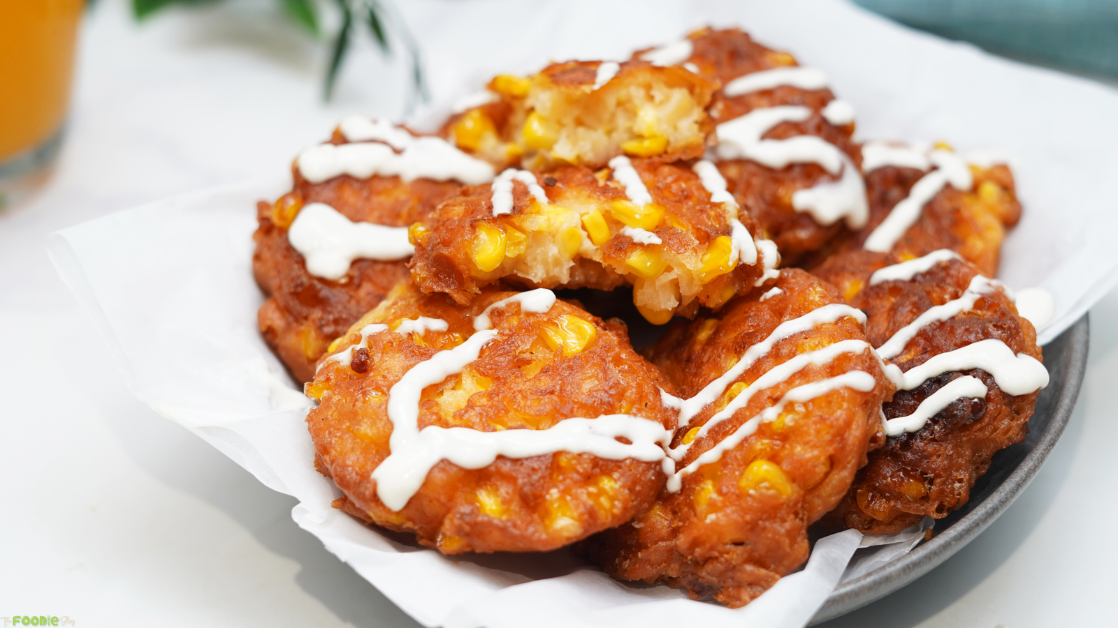Golden fried corn fritters stacked on a serving plate with crisp browned edges