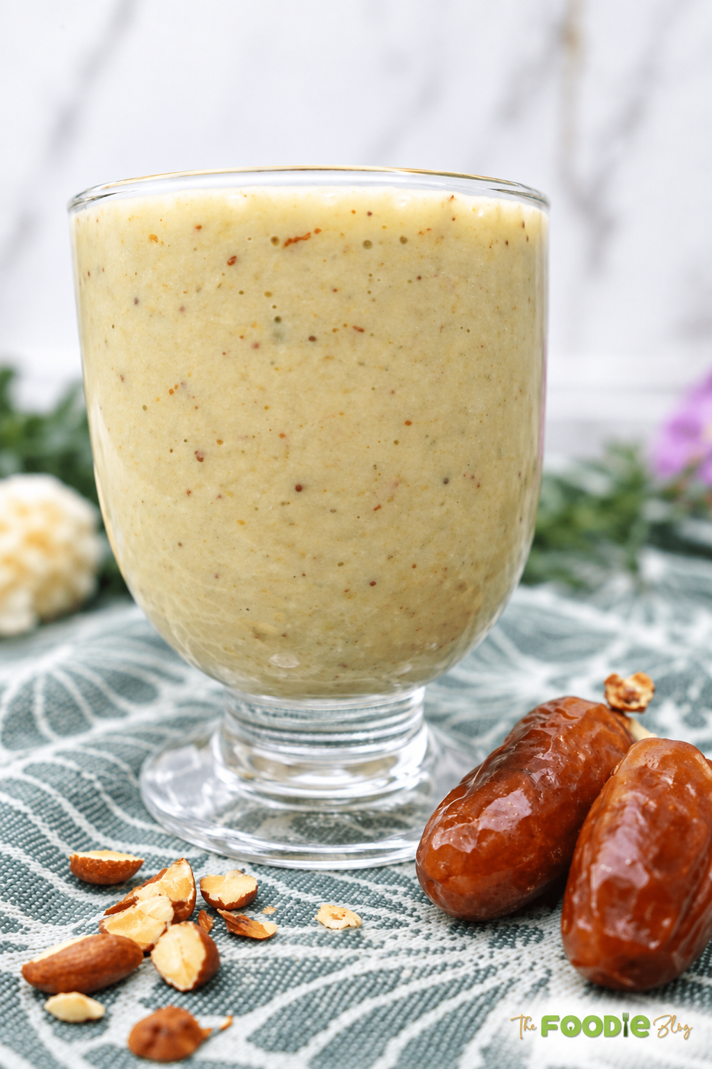 Avocado date almond drink in a glass with dates and chopped almonds