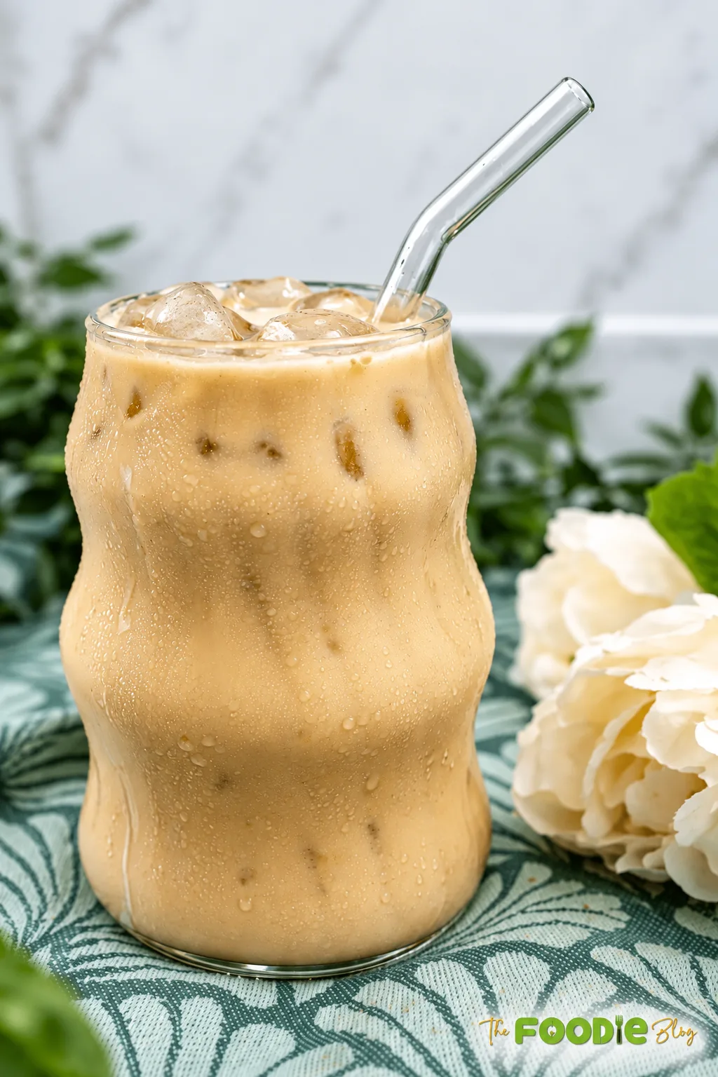 Creamy chill coffee with ice cubes served in a glass with a reusable straw