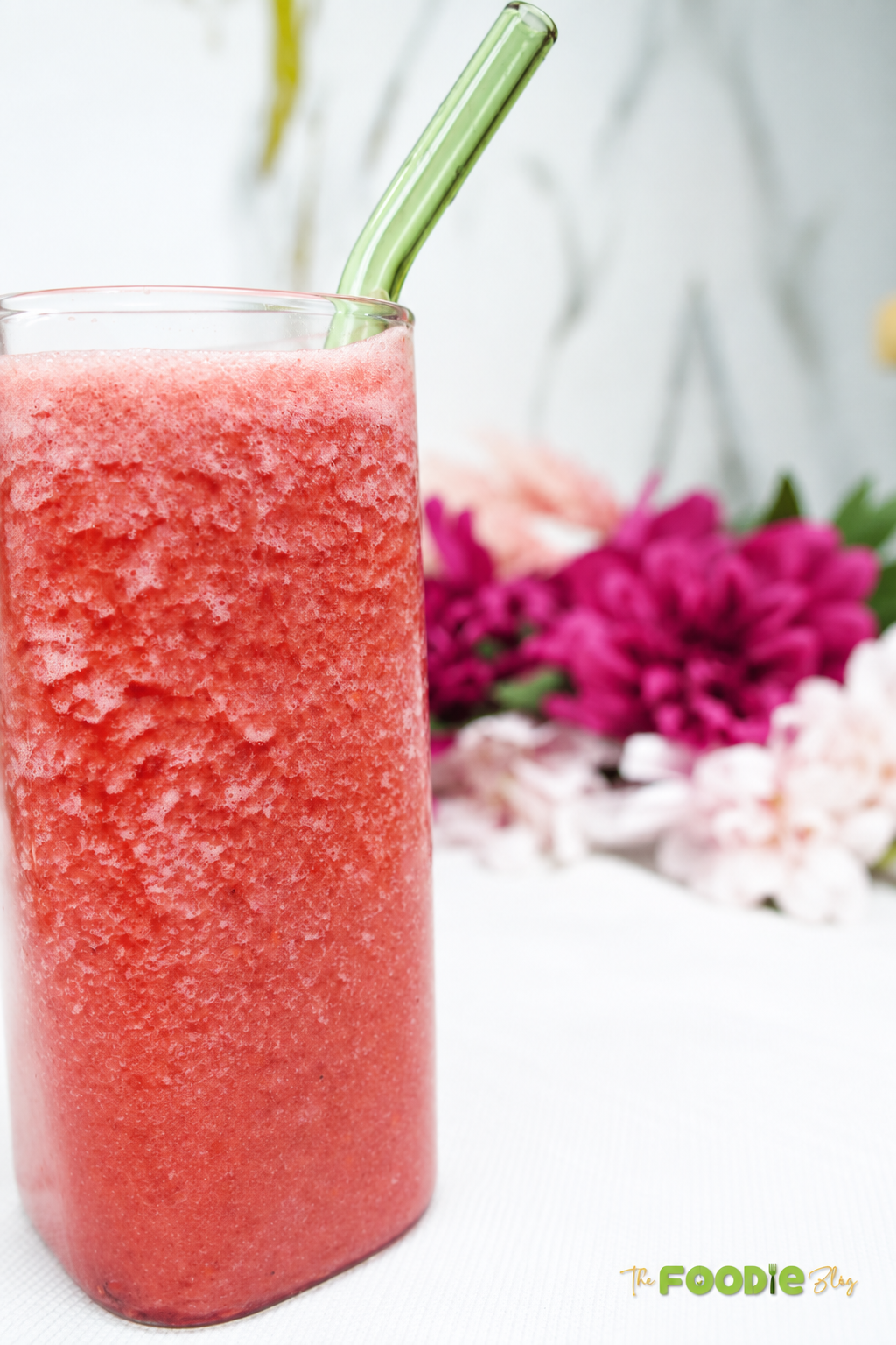 Homemade raspberry juice in a tall glass with a reusable straw