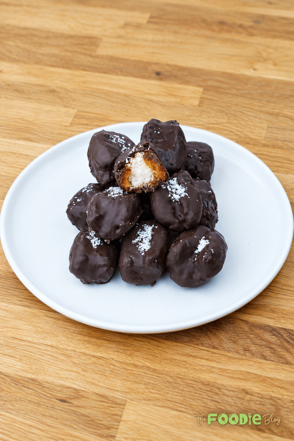 Homemade chocolate-covered dates filled with coconut and served on a white plate