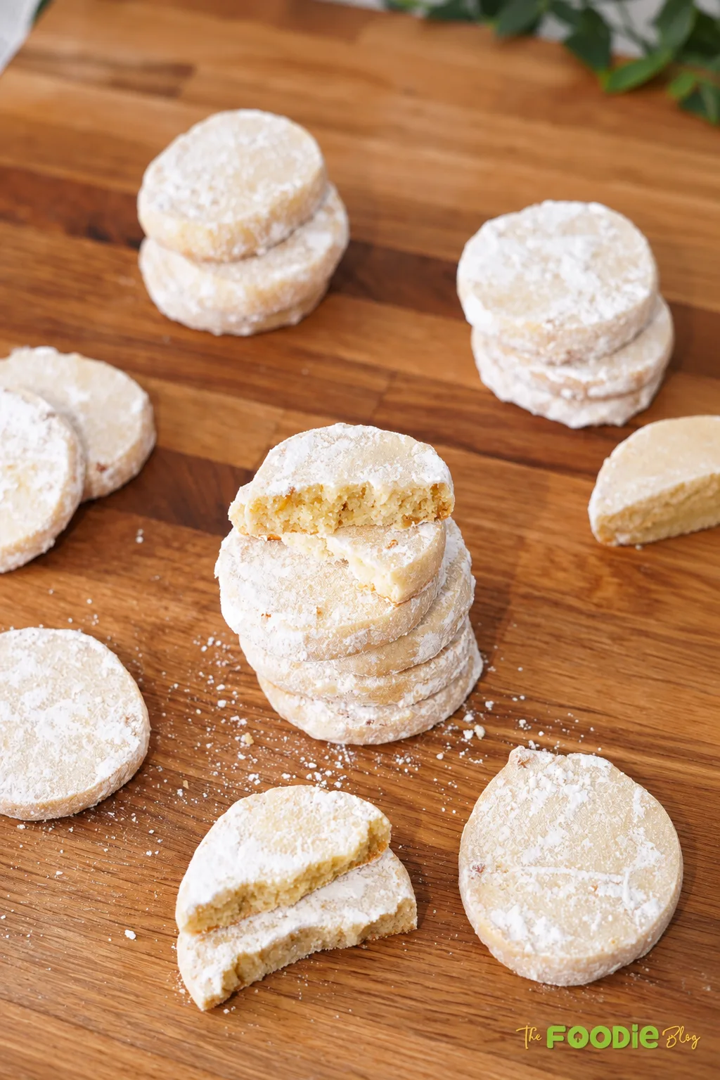 Stack of lime meltaway cookies with powdered sugar and broken cookies showing the soft crumb