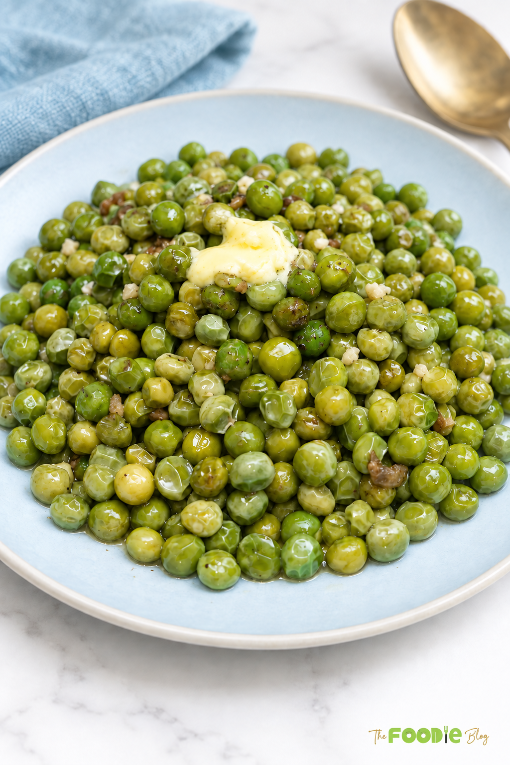 Garlic butter peas with melted butter served on a blue plate
