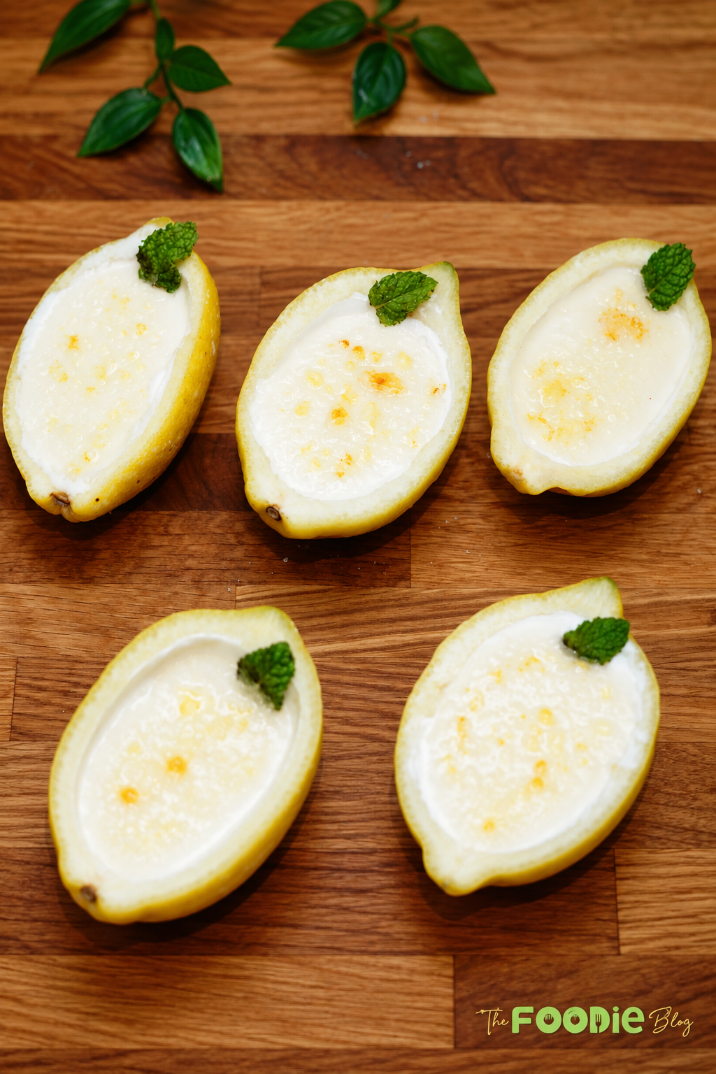 Lemon posset set inside hollowed lemon halves with fresh mint garnish