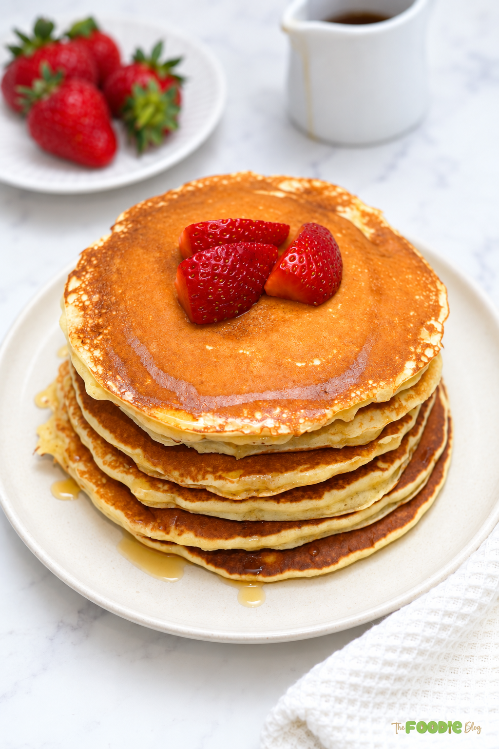 Fluffy protein pancakes with strawberries and syrup on a plate