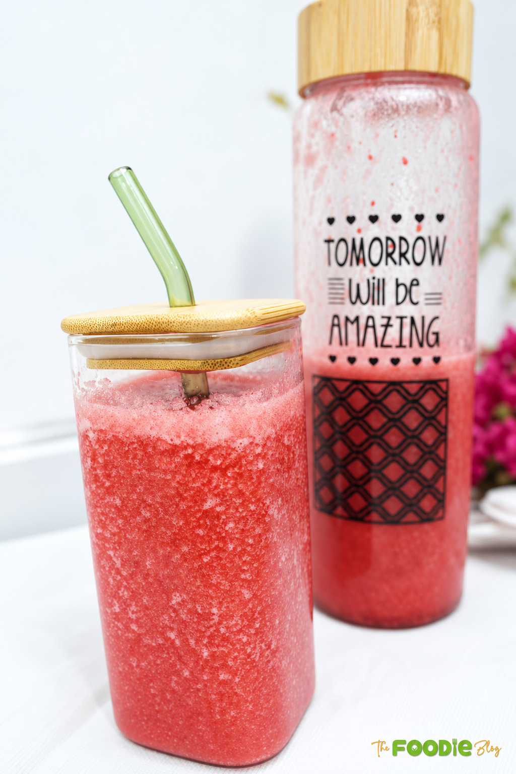 Fresh raspberry juice served in a glass with a bottle in the background