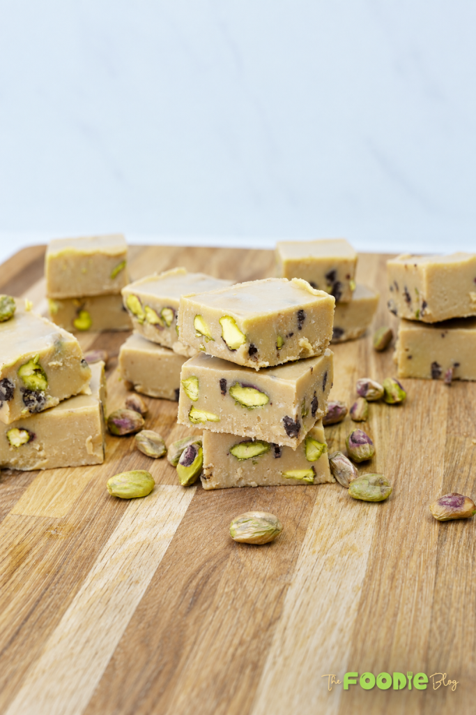 Homemade tahini fudge squares with pistachios and chocolate chips served on a wooden board