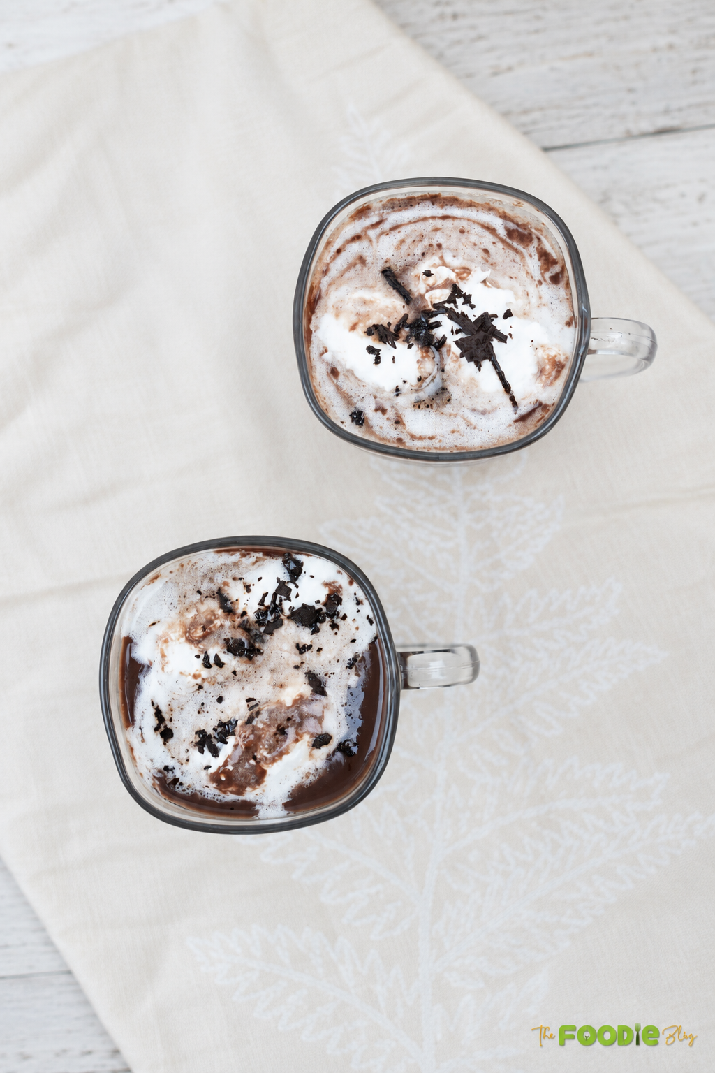 Two mugs of creamy homemade hot chocolate topped with whipped cream
