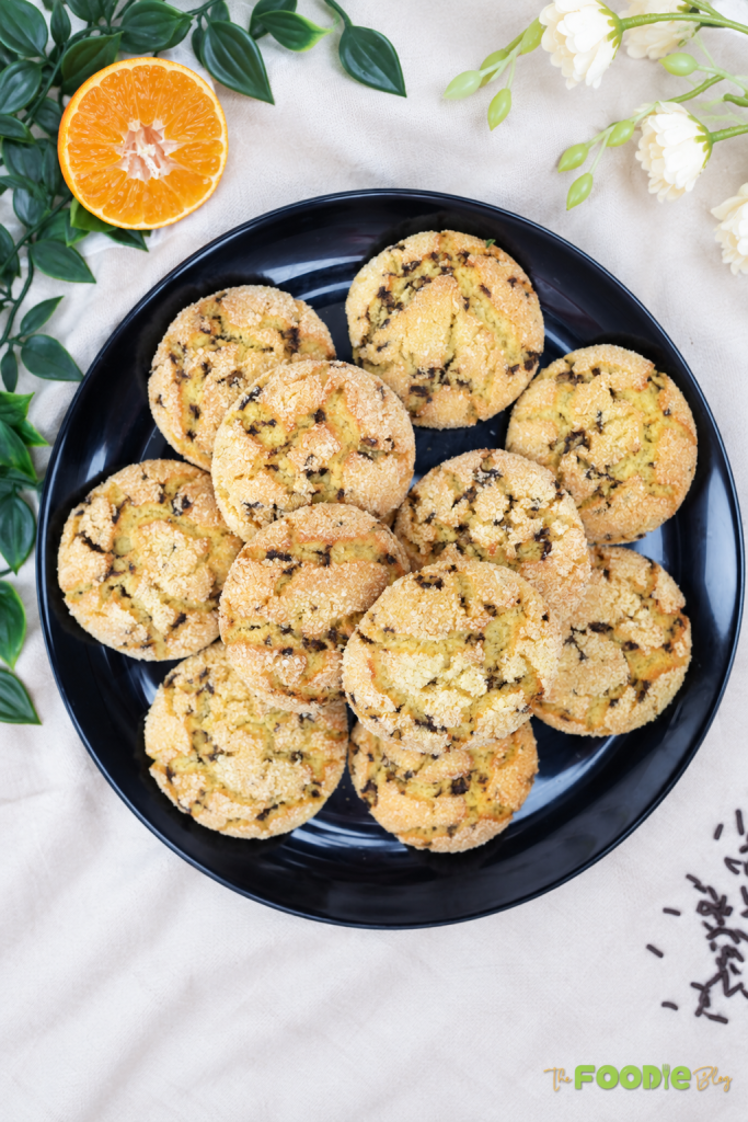 Homemade semolina cookies served on a black plate with orange garnish