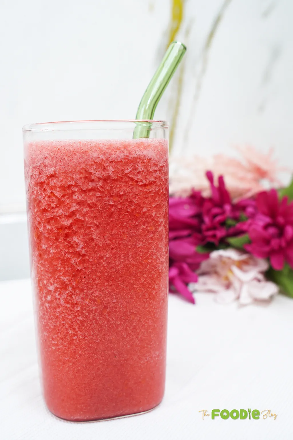 Chilled homemade raspberry juice in a tall glass with a green straw