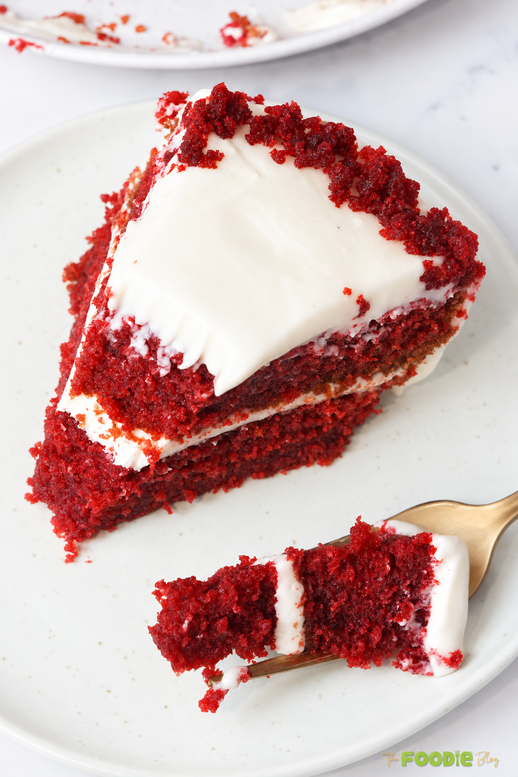 Close-up slice of moist red velvet cake with cream cheese frosting