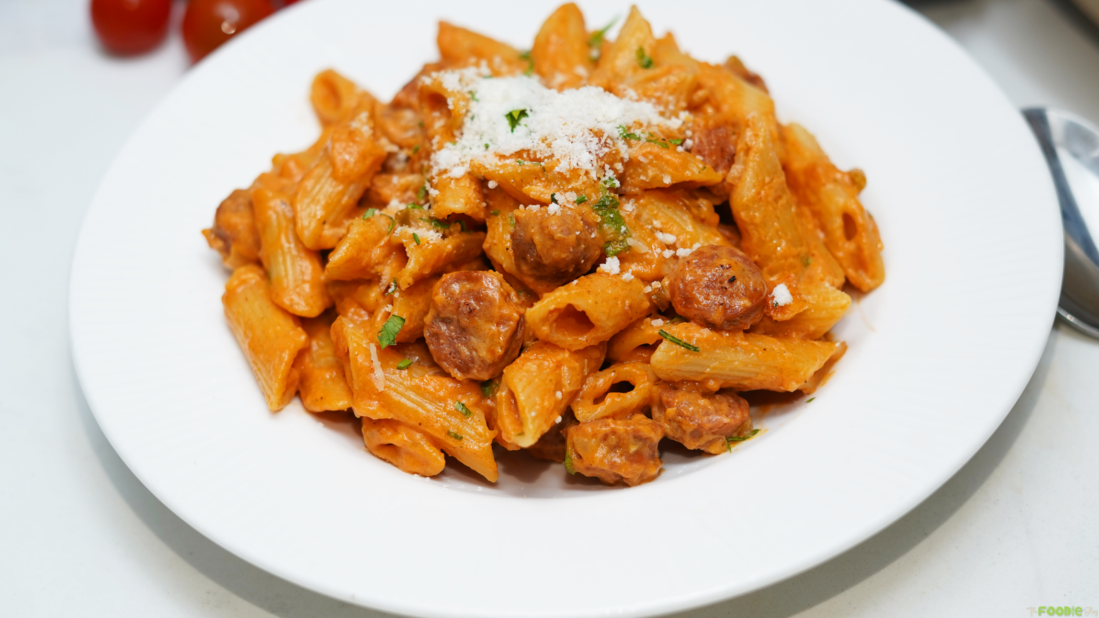 Cajun sausage pasta with creamy penne, browned smoked sausage, Parmesan, and parsley served in a white pasta bowl.