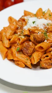 Close-up of creamy Cajun penne pasta with smoked sausage, Parmesan cheese, and fresh parsley.