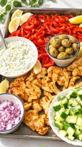 Chicken pita platter with roasted peppers, cucumber, red onion, olives, lemon, and tzatziki sauce.