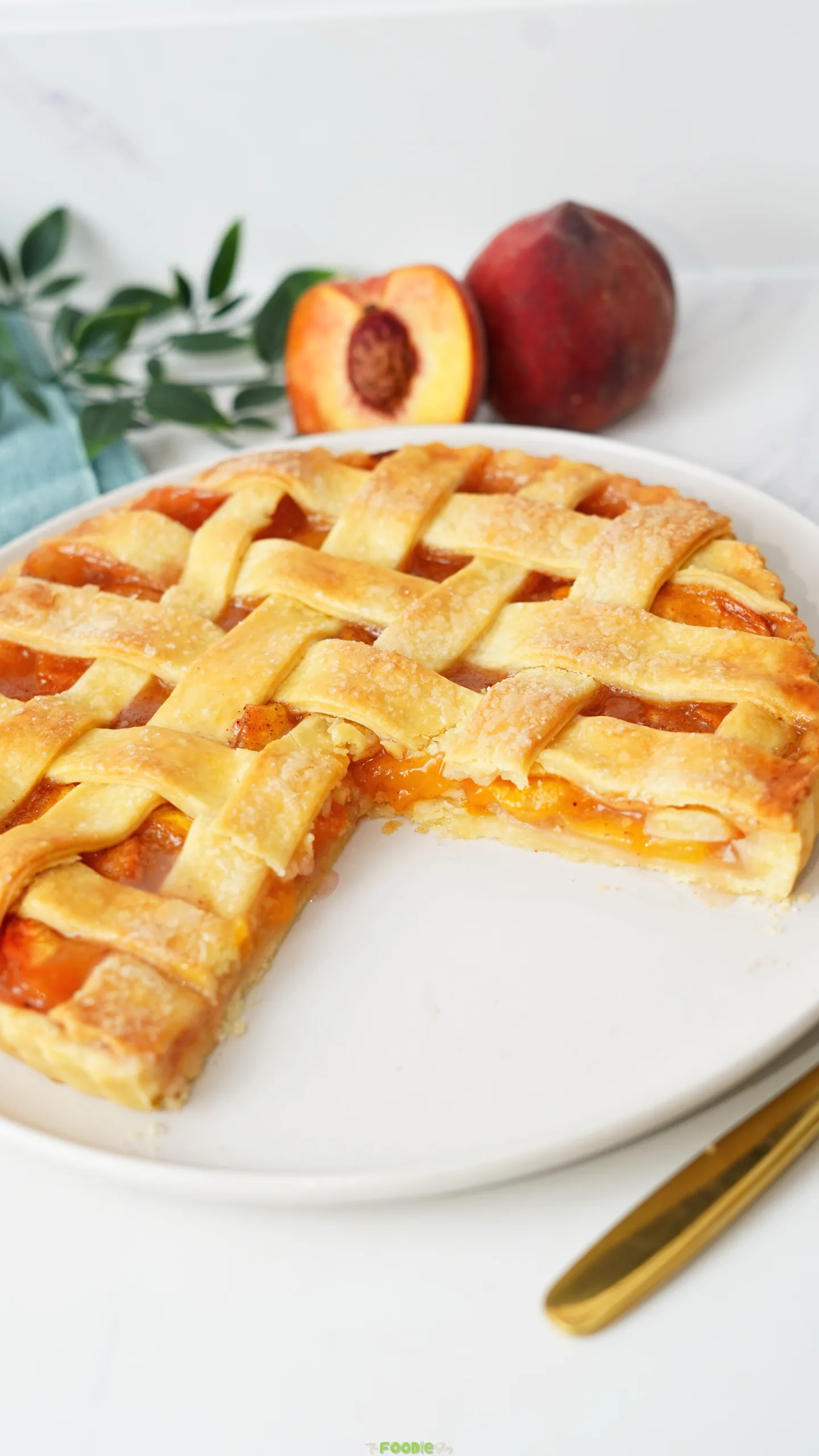 Golden lattice peach pie made with fresh peaches with one slice removed.