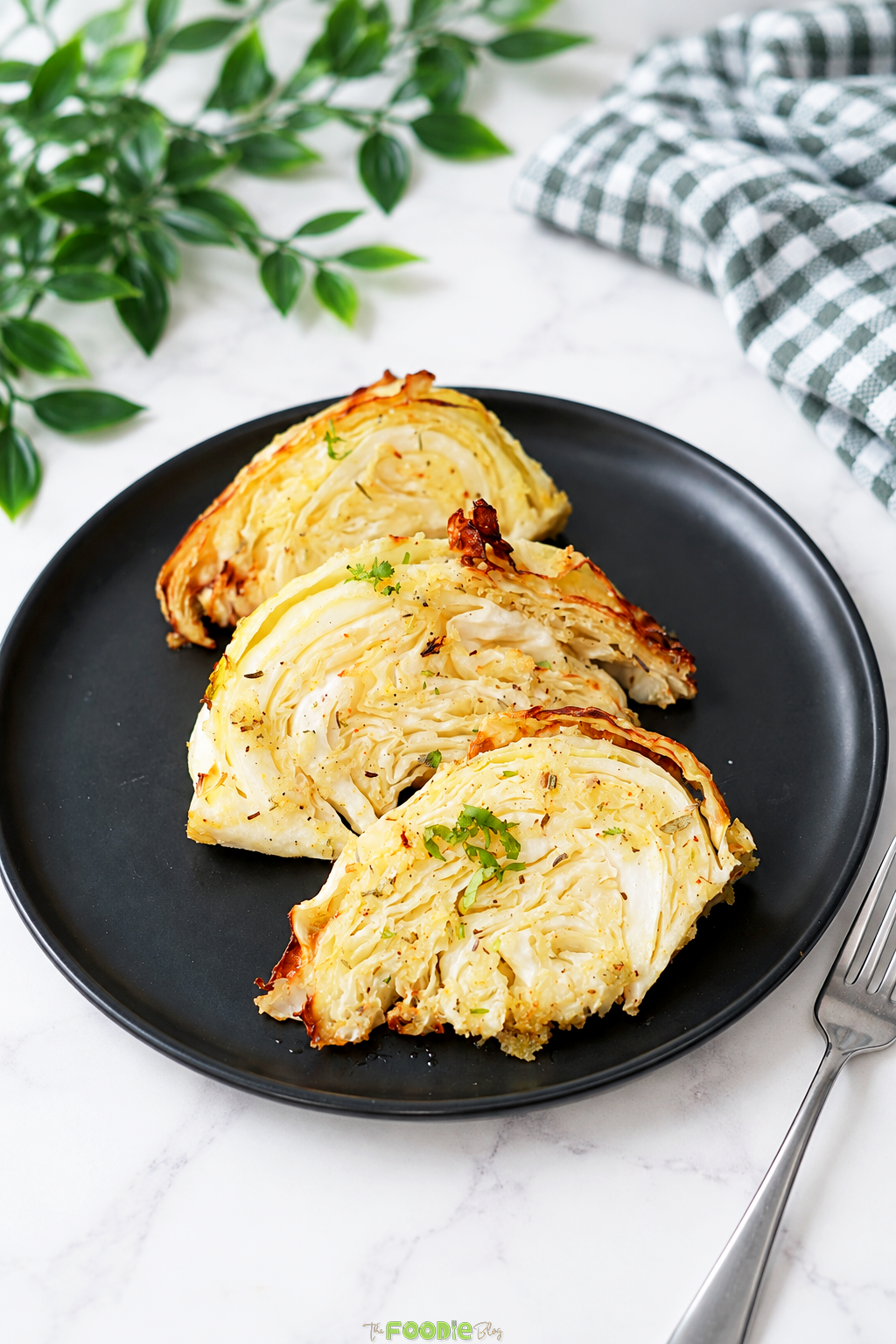Three garlic herb cabbage wedges served on a black plate after air frying.