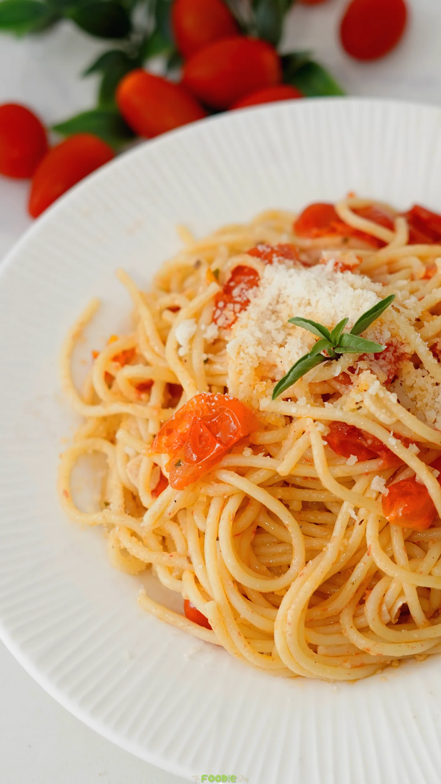 Close-up of garlic tomato pasta with cherry tomatoes and grated Parmesan cheese.