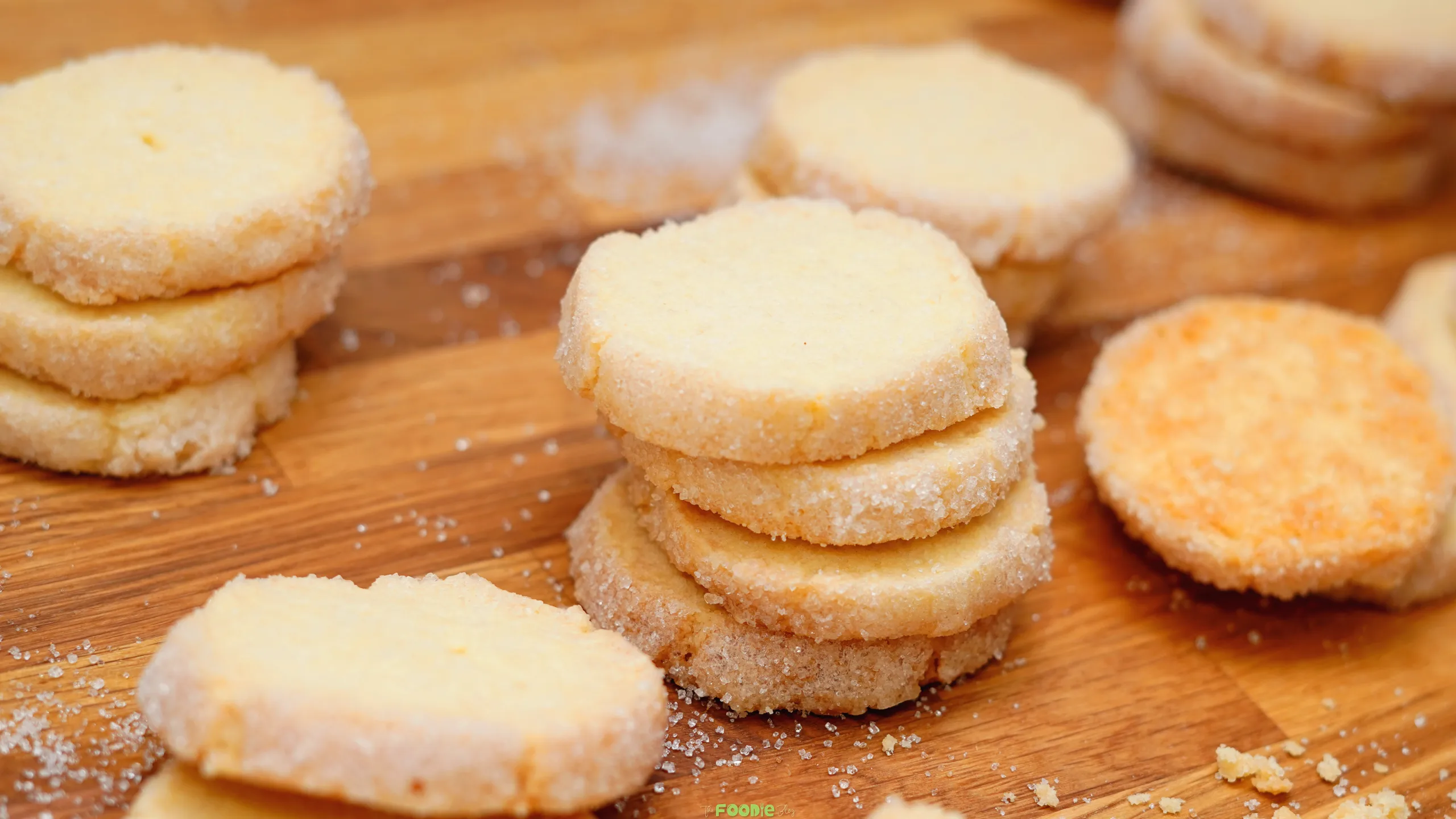 Homemade French sable cookies arranged in stacks on a wooden serving board.