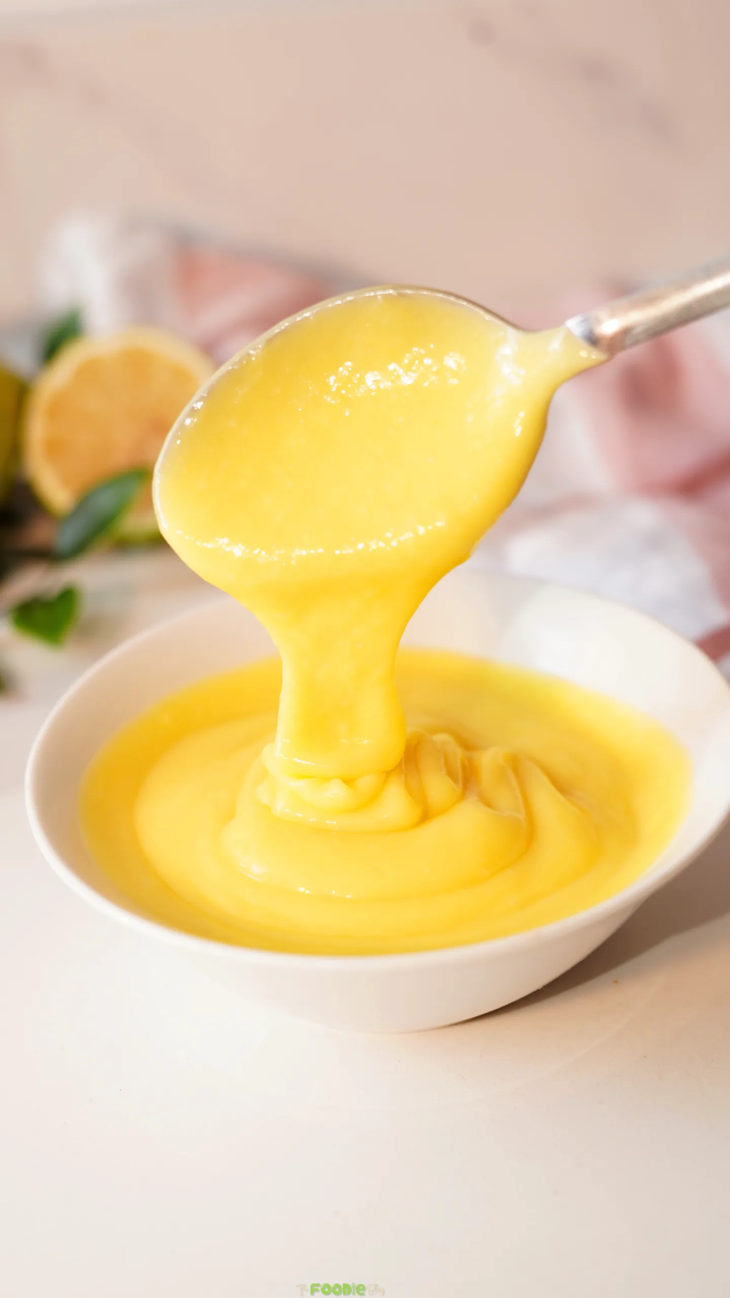 Thick homemade lime curd dripping from a spoon over a bowl.