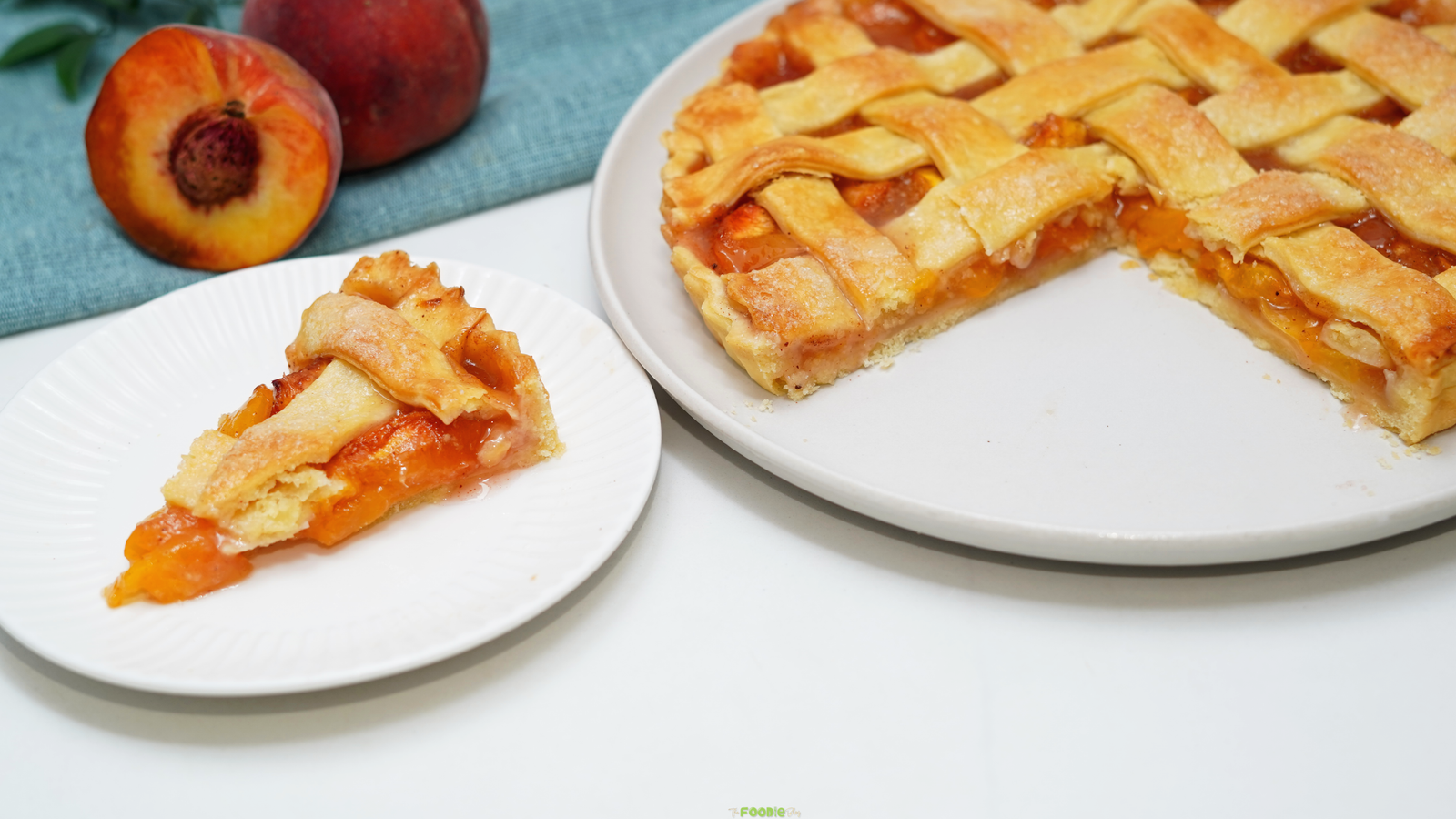 Slice of homemade peach pie with fresh peach filling beside the remaining lattice pie.