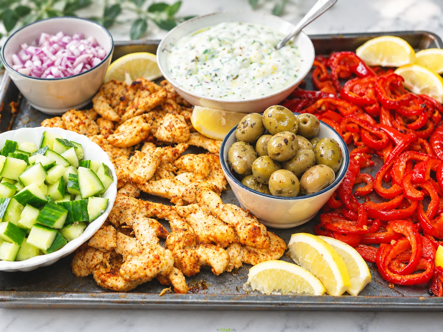 Mediterranean chicken pita platter with roasted chicken, red peppers, cucumber, olives, onion, lemon, and tzatziki.