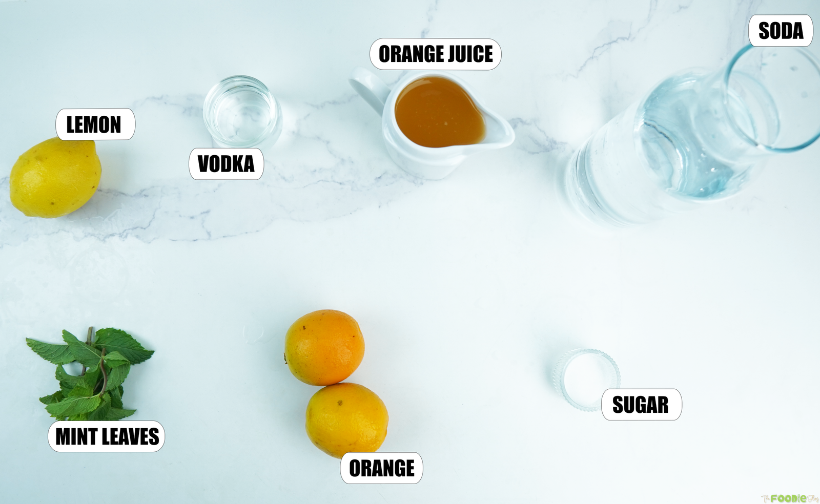 Vodka, orange juice, soda, lemon, mint leaves, fresh orange, and sugar arranged for an orange mojito.