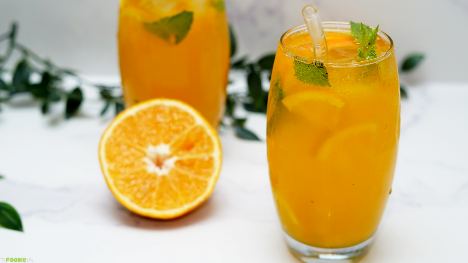 Orange mojito with vodka, orange juice, mint, citrus slices, ice, and soda served in a clear glass.