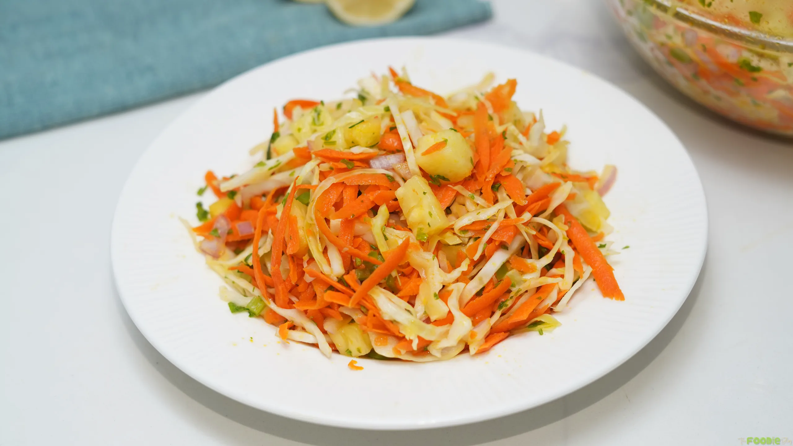 Fresh pineapple coleslaw with shredded cabbage, carrot, pineapple, red onion, jalapeño, and cilantro on a white plate.