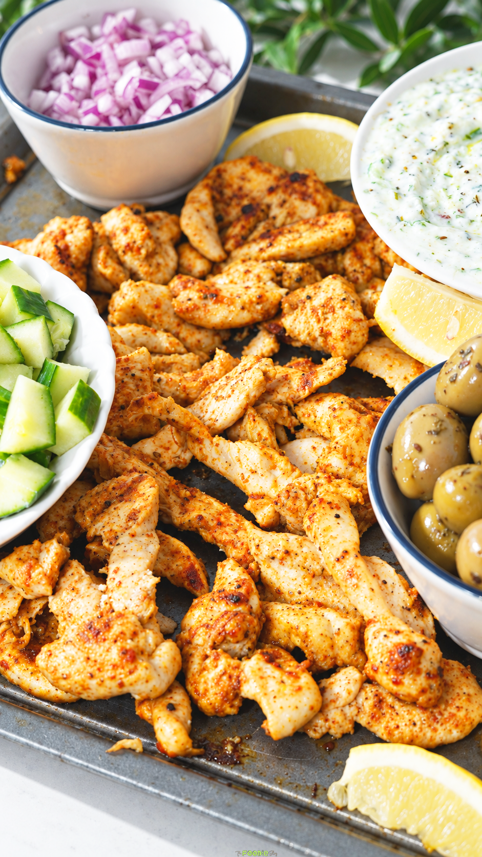 Seasoned sheet-pan chicken with cucumber, olives, red onion, lemon, and homemade tzatziki.