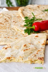 Close-up of homemade aloo paratha with golden-brown spots and a soft spiced potato filling visible inside the flatbread.