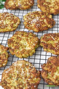 Crispy broccoli fritters cooling on a wire rack after frying.