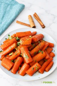 Homemade candied carrots glazed with brown sugar, butter, and cinnamon and garnished with parsley.