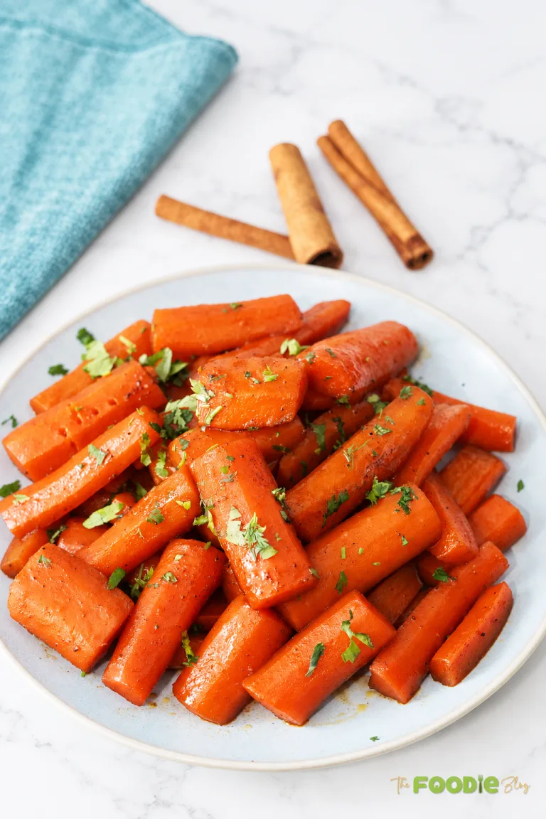 Homemade candied carrots glazed with brown sugar, butter, and cinnamon and garnished with parsley.