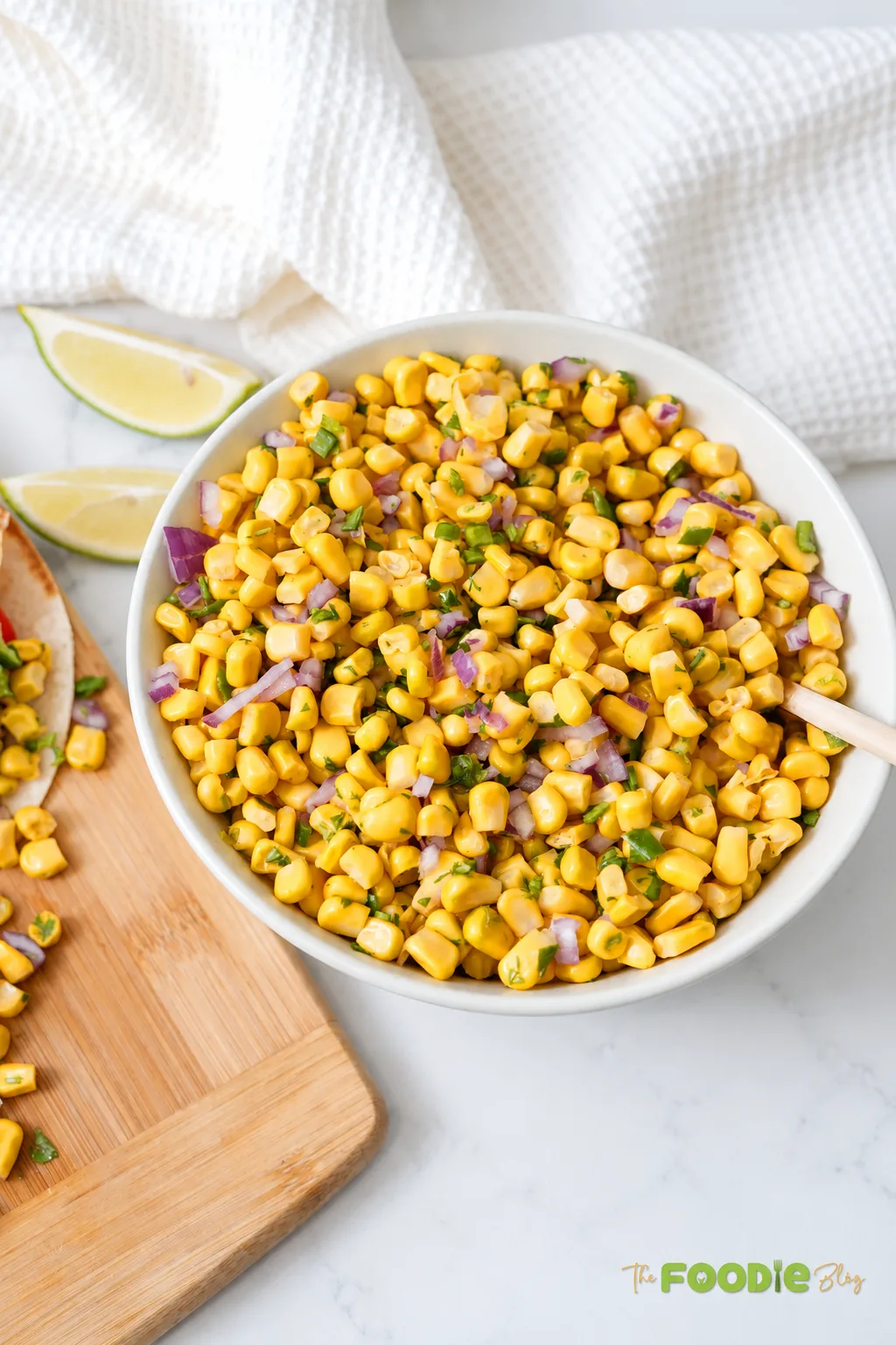 Homemade corn salsa served in a bowl with red onion, jalapeño, cilantro, and lime.