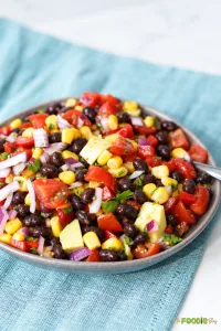 Cowboy caviar with black beans, corn, avocado, cherry tomatoes, red onion, and cilantro.