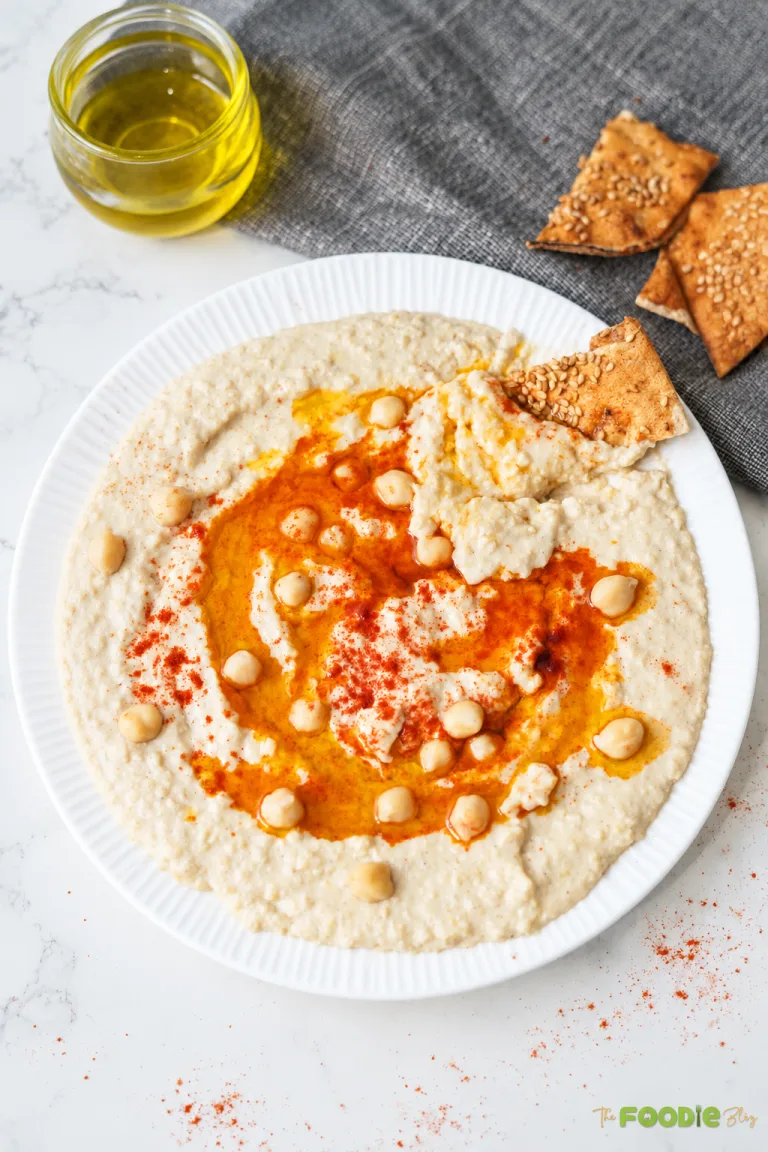 Creamy homemade hummus topped with chickpeas, olive oil, and paprika served with pita chips