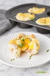 Croque Madame breakfast cup cut open to show a soft egg yolk, ham, melted Gruyere, and toasted bread.