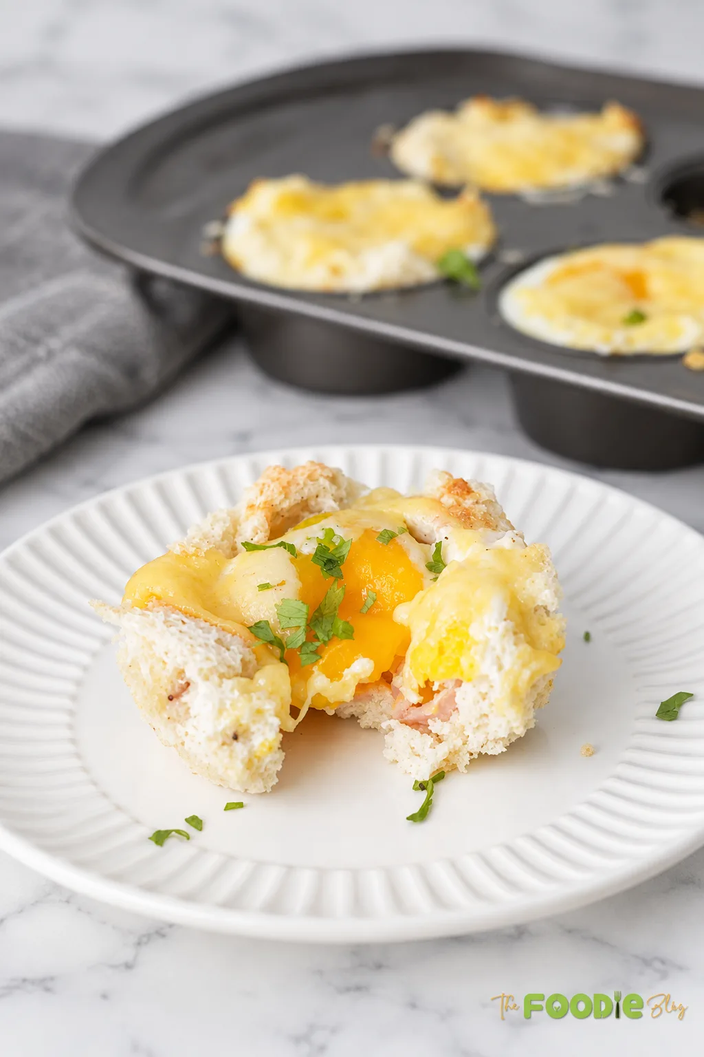 Croque Madame breakfast cup cut open to show a soft egg yolk, ham, melted Gruyere, and toasted bread.