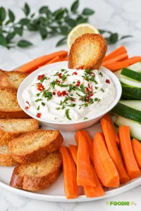 Creamy feta cream cheese dip served with toasted bread, carrots, and cucumber sticks.