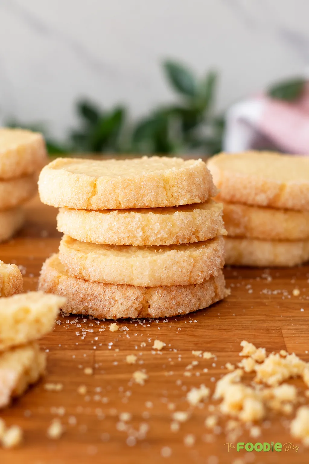 French sablé cookies stacked on a wooden board with crisp sugar-coated edges.