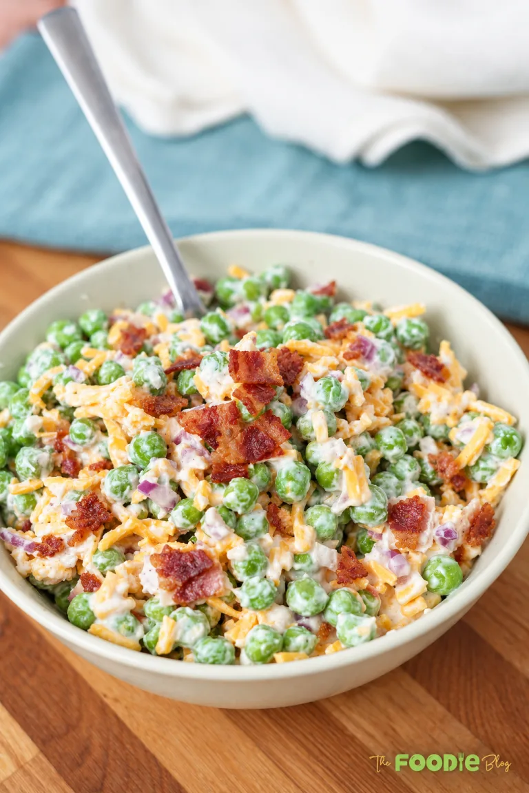Close-up of creamy pea salad with cheddar cheese, crispy bacon, and red onion.