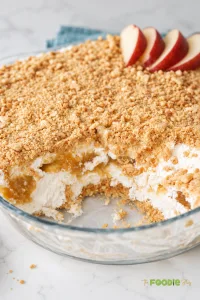 Close-up of no-bake peach dessert with creamy filling, peach layer, and crushed digestive biscuit topping.