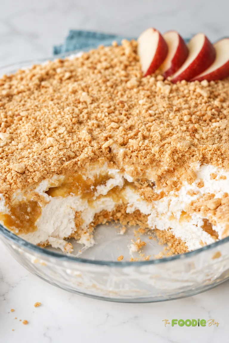 Close-up of no-bake peach dessert with creamy filling, peach layer, and crushed digestive biscuit topping.