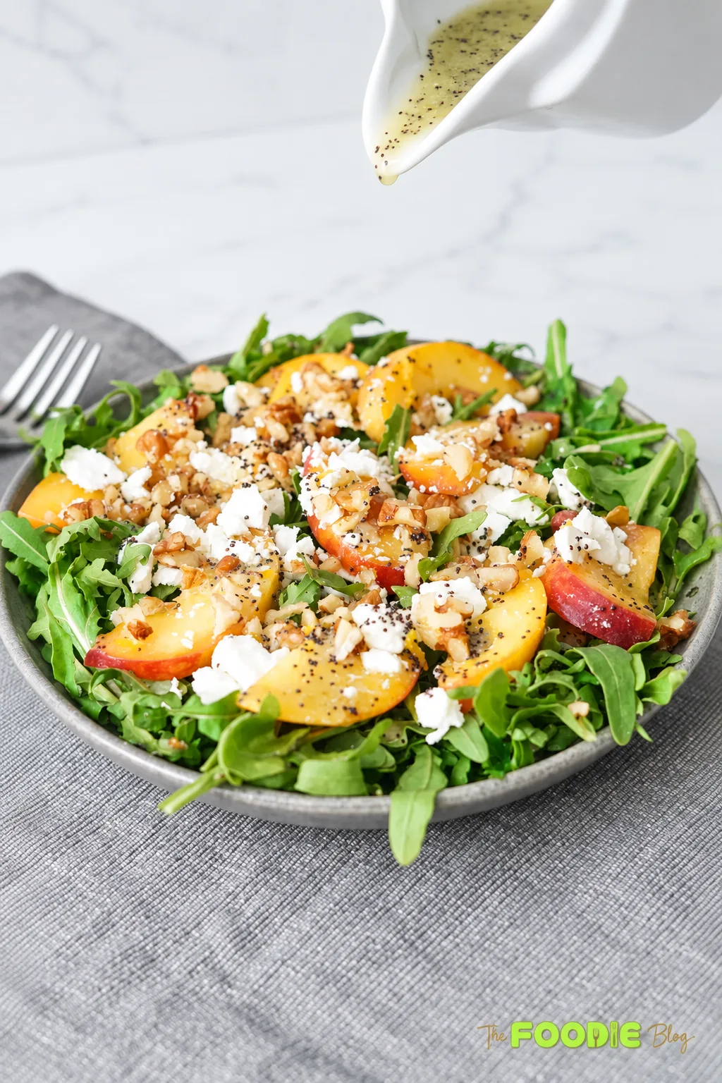 Fresh peach arugula salad with feta cheese, walnuts, and poppy seed dressing.