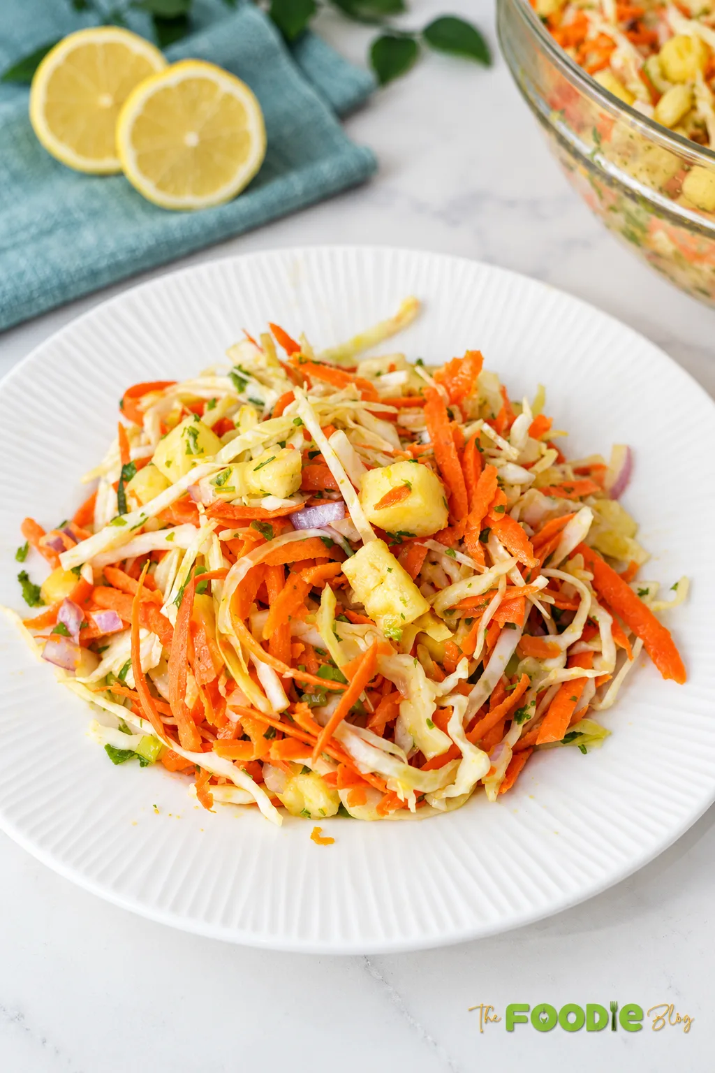 Fresh pineapple coleslaw with cabbage, carrots, red onion, cilantro, and pineapple served on a white plate.