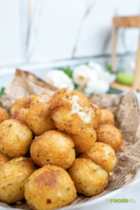 Crispy golden potato balls with herbs, including one broken open to show the soft potato center.