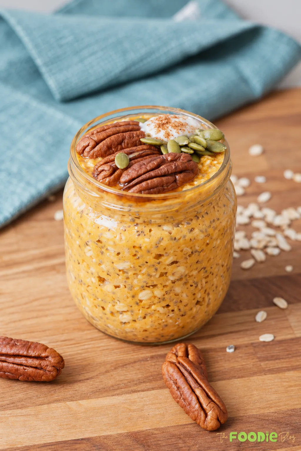 Pumpkin pie overnight oats topped with pecans, pepitas, Greek yogurt, and pumpkin pie spice in a glass jar.