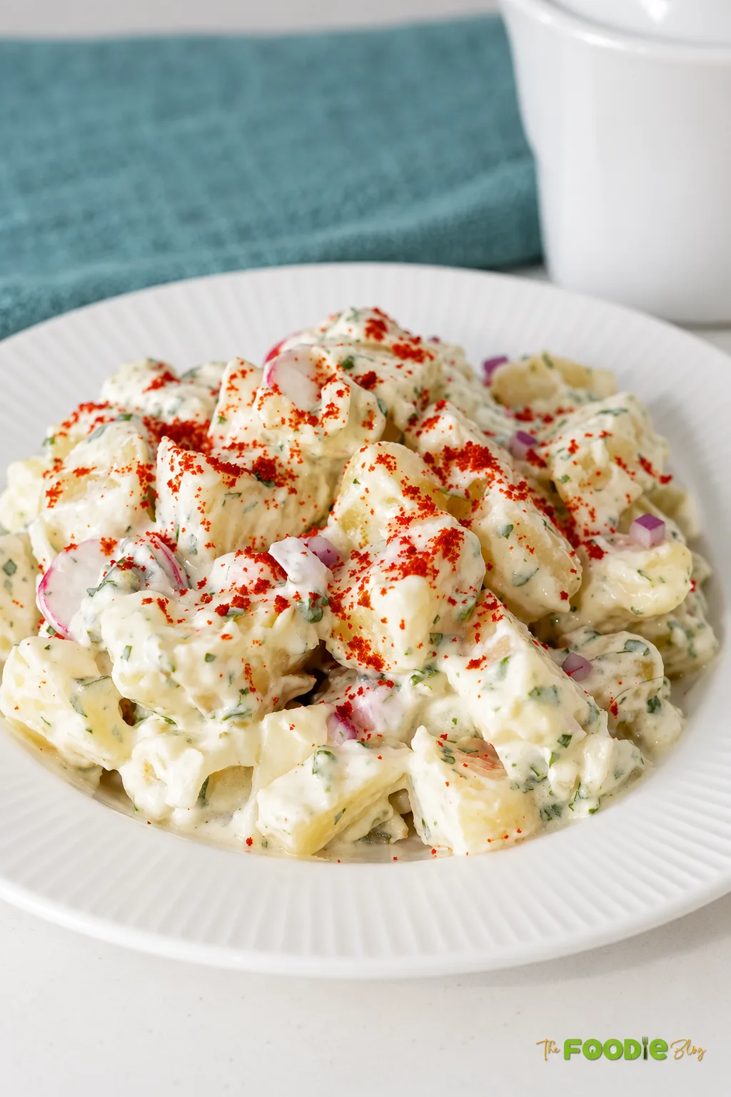 Creamy red potato salad with radishes, red onion, fresh parsley, and smoked paprika.