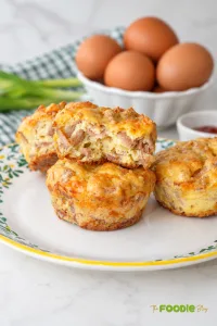 Breakfast sausage muffins with eggs and cheddar cheese served on a plate with one muffin cut open.