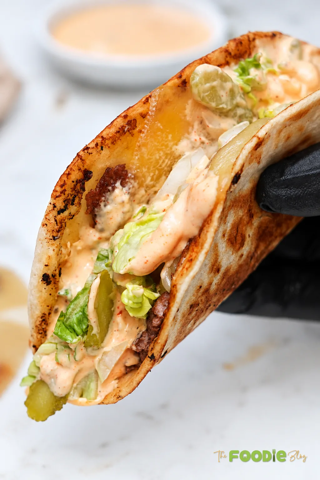 Smash burger tacos with ground beef, melted cheese, lettuce, pickles, onions, and creamy burger sauce on toasted flour tortillas.